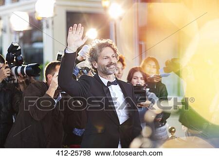 Stock Photo - Celebrity waving for paparazzi at event. Fotosearch