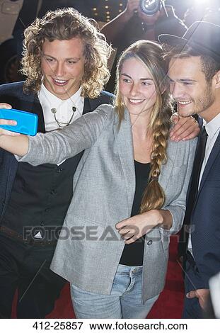 Stock Photo - Fan taking selfie with celebrities at event. Fotosearch