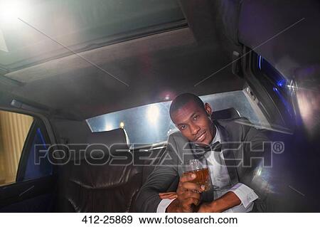 Portrait of confident celebrity drinking cocktail inside limousine outside event View Large Photo Image Stock Photo - Portrait of confident celebrity drinking cocktail inside limousine outside event. Fotosearch