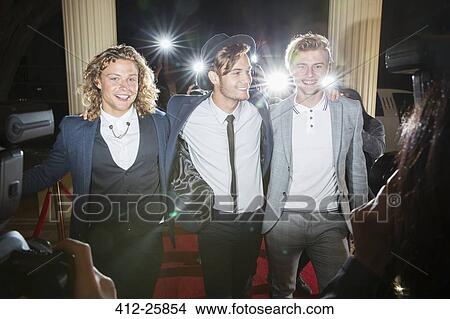 Picture - Portrait of smiling celebrities being photographed by paparazzi at red carpet event. Fotosearch