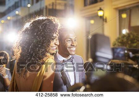 Stock Photo - Smiling celebrity couple being interviewed and photographed by paparazzi at event. Fotosearch