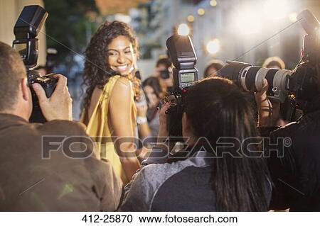 Stock Image - Smiling celebrity turning towards photographing paparazzi photographers. Fotosearch