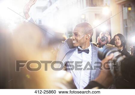 Smiling celebrity waving to paparazzi photographers at event View Large Photo Image Stock Image - Smiling celebrity waving to paparazzi photographers at event. Fotosearch