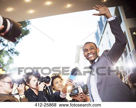 Waving celebrity being interviewed and photographed by paparazzi at event View Large Photo Image Stock Photo - Waving celebrity being interviewed and photographed by paparazzi at event. Fotosearch
