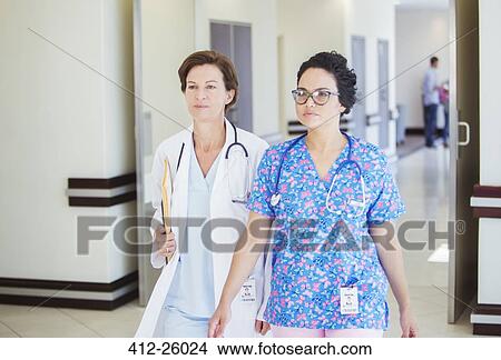 Picture - Doctor and nurse walking together in hospital corridor. Fotosearch