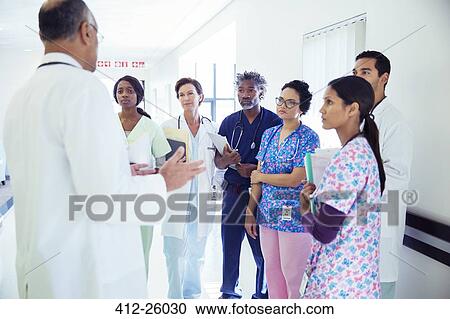 Doctor leading team meeting in hospital corridor View Large Photo Image Stock Image - Doctor leading team meeting in hospital corridor. Fotosearch