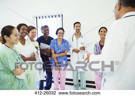 Doctor leading team meeting in hospital corridor View Large Photo Image Stock Image - Doctor leading team meeting in hospital corridor. Fotosearch