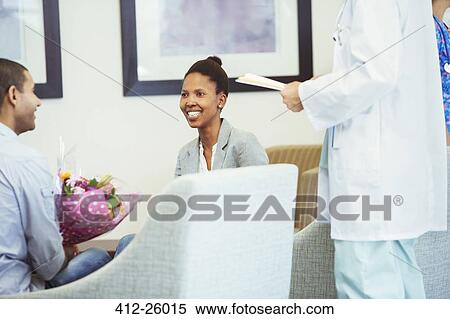Stock Photography - Doctor meeting with smiling couple in hospital waiting room. Fotosearch