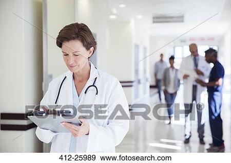 Doctor using digital tablet in hospital corridor View Large Photo Image Stock Photo - Doctor using digital tablet in hospital corridor. Fotosearch