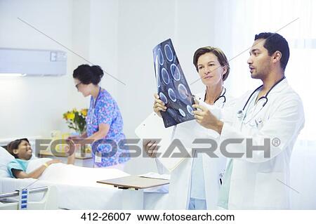 Doctors reviewing MRI scans in hospital room View Large Photo Image Stock Photo - Doctors reviewing MRI scans in hospital room. Fotosearch