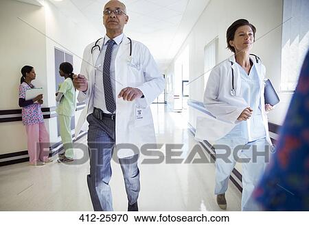 Stock Image - Doctors running down hospital corridor. Fotosearch