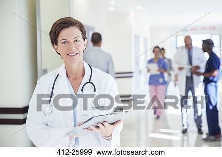 Portrait of confident doctor with clipboard in hospital corridor View Large Photo Image Stock Photo - Portrait of confident doctor with clipboard in hospital corridor. Fotosearch