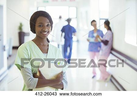Stock Image - Portrait of smiling nurse in hospital corridor. Fotosearch