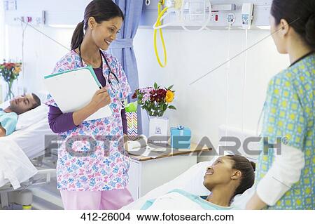 Smiling nurses talking with patient in hospital room View Large Photo Image Picture - Smiling nurses talking with patient in hospital room. Fotosearch