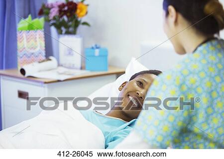 Stock Photography - Smiling patient in hospital bed smiling at nurse. Fotosearch