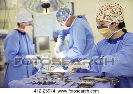 Picture - Surgeon at tray of surgical scissors in operating room. Fotosearch