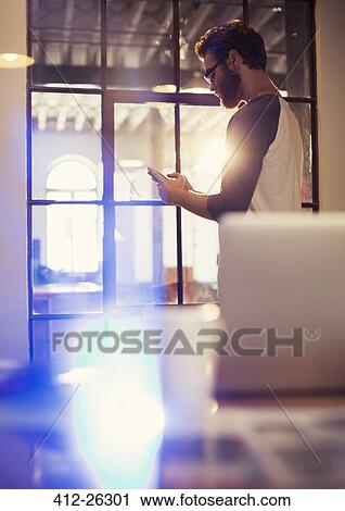 Stock Image - Casual businessman texting with cell phone in office. Fotosearch