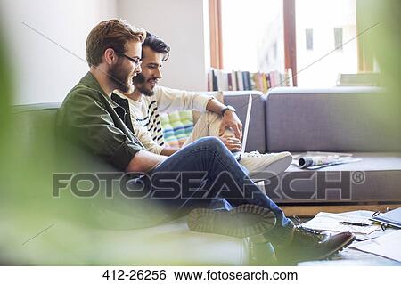 Stock Photograph - Casual businessmen using laptop on sofa. Fotosearch