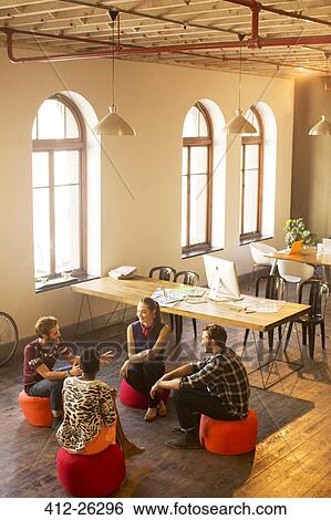 Stock Photograph - Creative business people talking in circle in office. Fotosearch