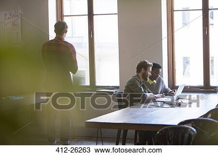 Creative business people working at laptop in office View Large Photo Image Stock Image - Creative business people working at laptop in office. Fotosearch