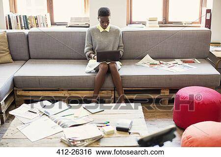 Creative businesswoman typing on digital tablet on sofa in office View Large Photo Image Stock Photograph - Creative businesswoman typing on digital tablet on sofa in office. Fotosearch