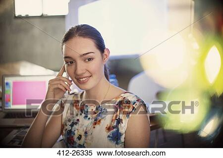 Stock Photography - Smiling businesswoman talking on cell phone in office. Fotosearch