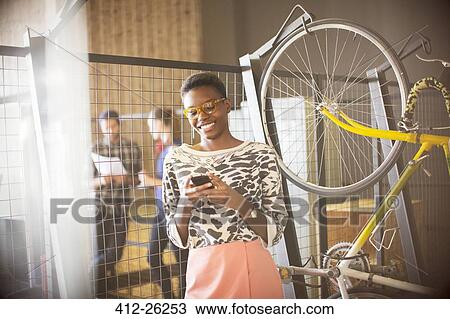 Smiling businesswoman texting on cell phone next to bicycle View Large Photo Image Stock Image - Smiling businesswoman texting on cell phone next to bicycle. Fotosearch
