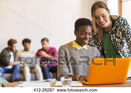 Stock Photo - Smiling creative businesswomen working at laptop in office. Fotosearch