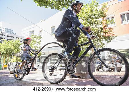 Businessman father in suit riding tandem bicycle with son on urban sidewalk View Large Photo Image Stock Photo - Businessman father in suit riding tandem bicycle with son on urban sidewalk. Fotosearch