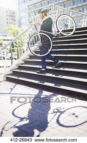 Businessman in suit and helmet carrying bicycle down urban stairs View Large Photo Image Stock Image - Businessman in suit and helmet carrying bicycle down urban stairs. Fotosearch