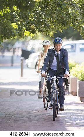 Businessman in suit and helmet riding bicycle on path View Large Photo Image Stock Image - Businessman in suit and helmet riding bicycle on path. Fotosearch