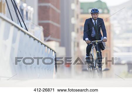 Businessman in suit and helmet riding bicycle in city View Large Photo Image Stock Image - Businessman in suit and helmet riding bicycle in city. Fotosearch