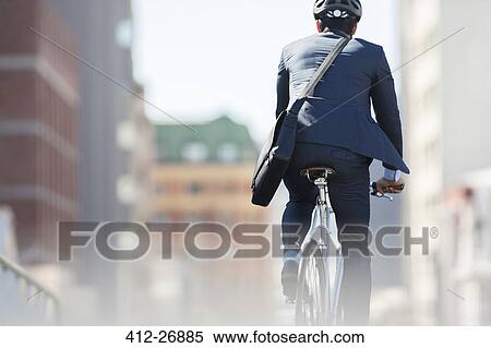 Stock Photography - Businessman in suit and helmet riding bicycle in city. Fotosearch