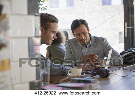Stock Image - Businessmen with coffee working at laptop in cafe. Fotosearch