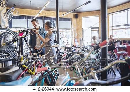 Picture - Couple browsing bicycles on rack in bicycle shop. Fotosearch
