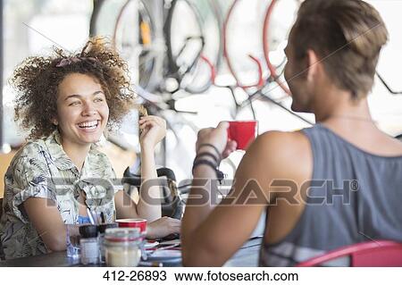 Stock Image - Couple drinking coffee and talking in cafe. Fotosearch