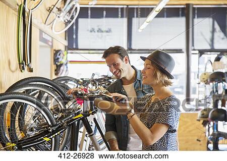 Couple looking at price tags on bicycles in bicycle shop View Large Photo Image Stock Photo - Couple looking at price tags on bicycles in bicycle shop. Fotosearch