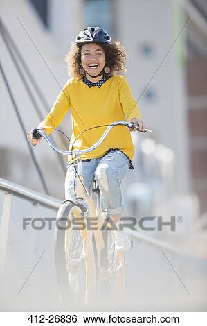 Stock Photograph - Enthusiastic woman in helmet riding bicycle. Fotosearch