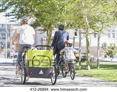 Families riding bicycles in sunny urban park View Large Photo Image Picture - Families riding bicycles in sunny urban park. Fotosearch