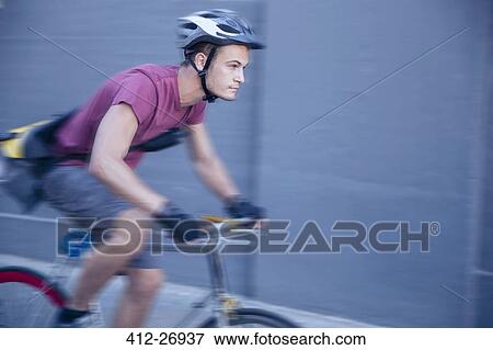 Stock Photo - Focused bicycle messenger with helmet on the move. Fotosearch