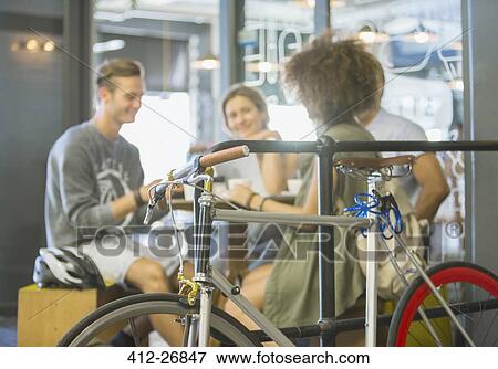 Friends hanging out at cafe behind bicycle View Large Photo Image Stock Photo - Friends hanging out at cafe behind bicycle. Fotosearch