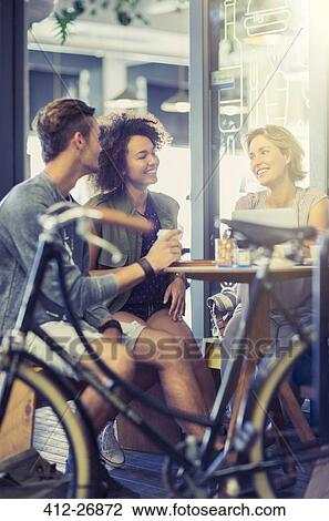 Friends hanging out at cafe table behind bicycle View Large Photo Image Stock Image - Friends hanging out at cafe table behind bicycle. Fotosearch