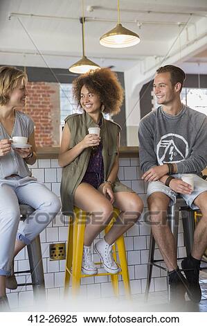 Stock Photography - Friends hanging out talking and drinking coffee in cafe. Fotosearch