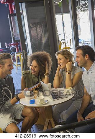 Friends with digital tablet and laptop hanging out at cafe View Large Photo Image Stock Photo - Friends with digital tablet and laptop hanging out at cafe. Fotosearch