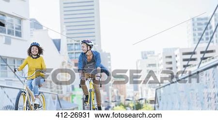 Friends with helmets riding bicycles over urban footbridge View Large Photo Image Stock Image - Friends with helmets riding bicycles over urban footbridge. Fotosearch