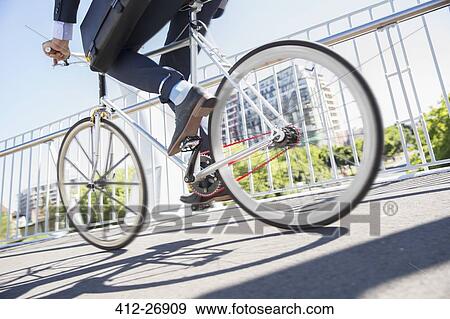 Low section businessman in suit riding bicycle on sunny urban sidewalk View Large Photo Image Stock Photo - Low section businessman in suit riding bicycle on sunny urban sidewalk. Fotosearch