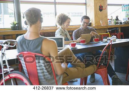 Stock Photo - People using digital tablets in cafe. Fotosearch