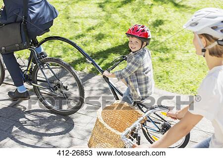 Portrait smiling boy riding tandem bicycle with father in park View Large Photo Image Stock Image - Portrait smiling boy riding tandem bicycle with father in park. Fotosearch