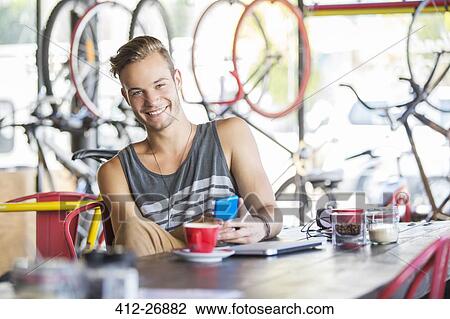 Portrait smiling man with coffee and cell phone in bicycle shop View Large Photo Image Stock Image - Portrait smiling man with coffee and cell phone in bicycle shop. Fotosearch