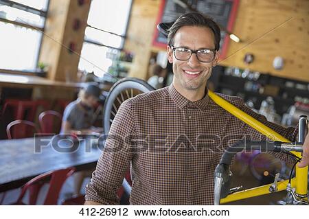 Portrait smiling man with eyeglasses carrying bicycle in cafe View Large Photo Image Stock Image - Portrait smiling man with eyeglasses carrying bicycle in cafe. Fotosearch